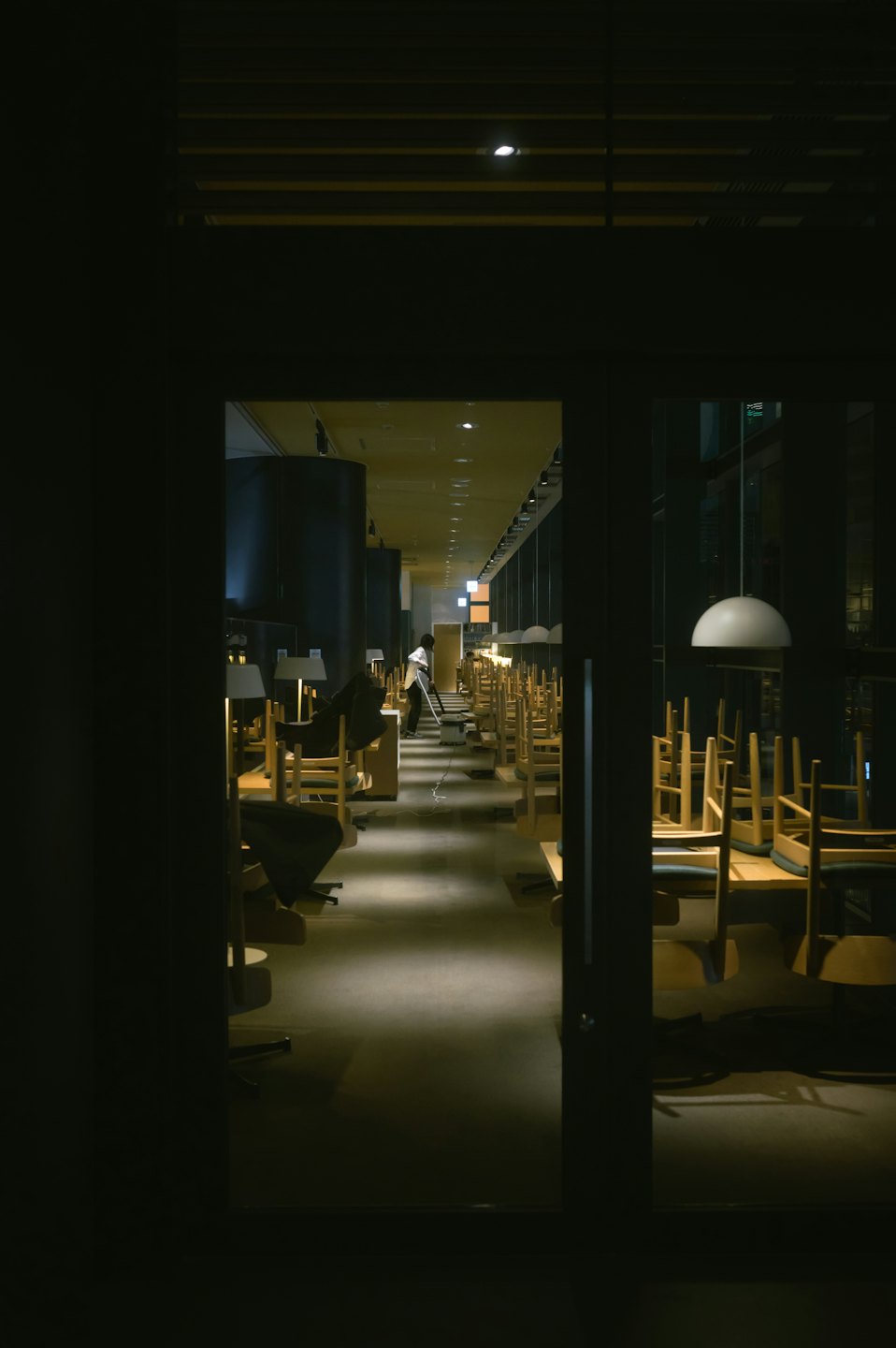 Persona che aspira un ristorante moderno dopo l'orario di chiusura.